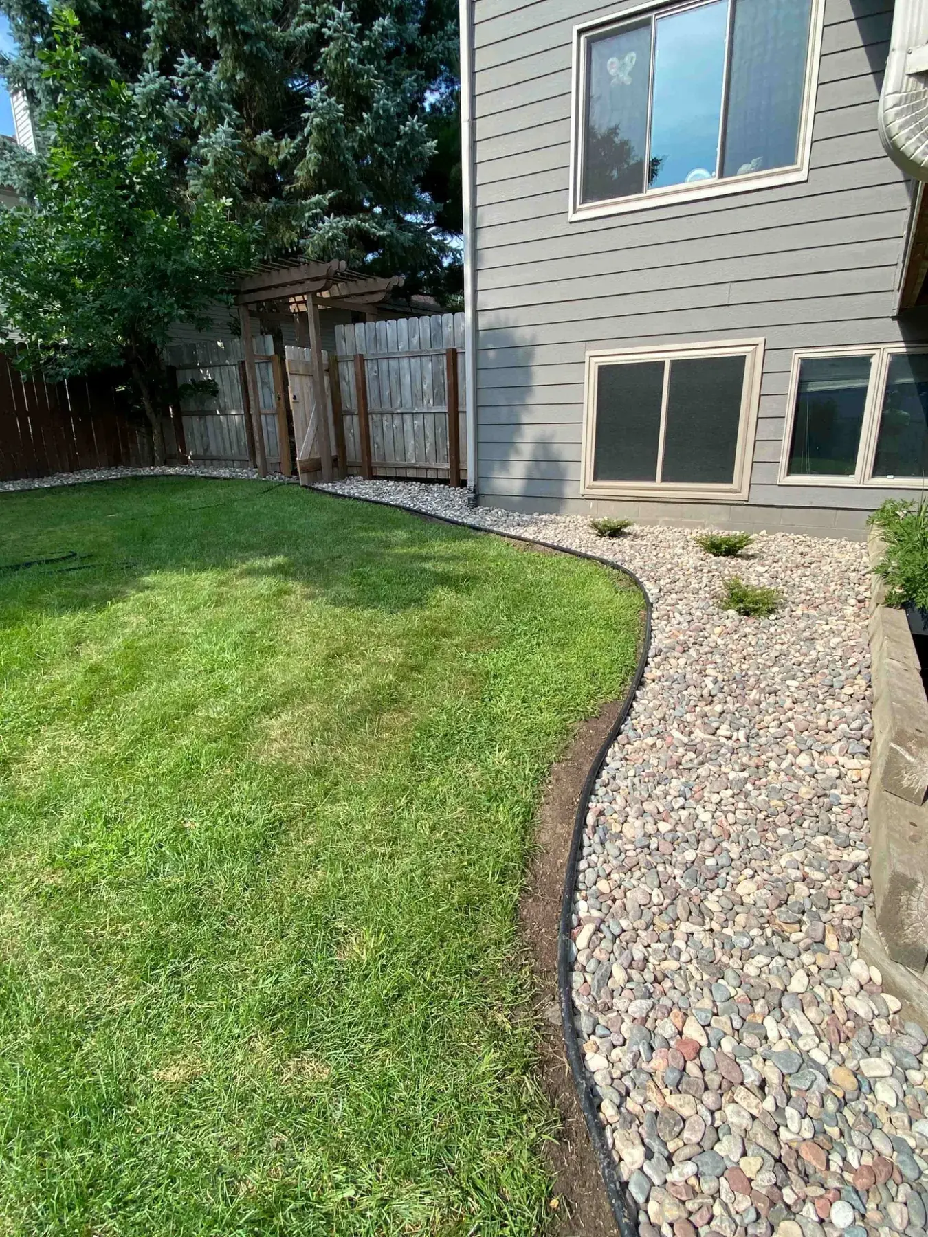 Curved backyard rock landscaping completed by Minnlawn